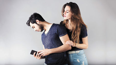 Hombre viendo su celular a espaldas de su pareja